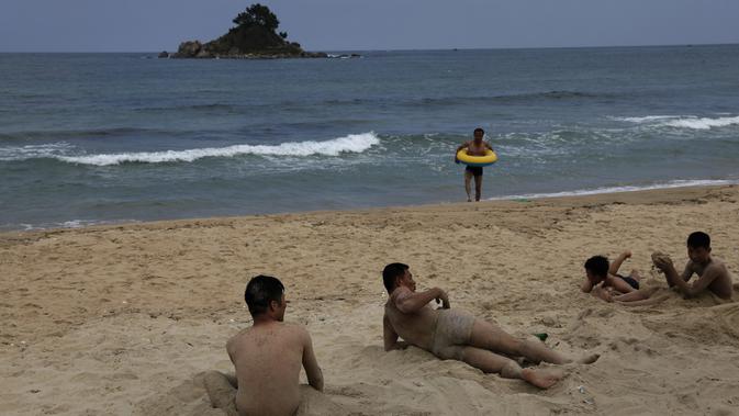 Sejumlah pria bermain pasir saat menikmati akhir pekan di pantai Sijung Ho di Korea Utara (14/7/2019). Pantai Sijung Ho merupakan tujuan wisata populer bagi penduduk lokal dan asing. (AP Photo/Vincent Yu)
