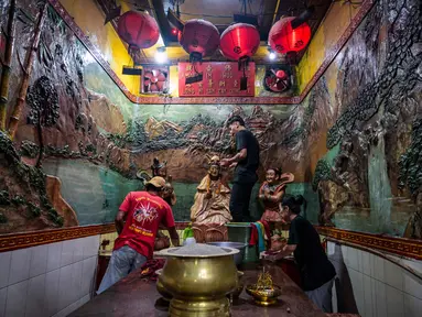 Para sukarelawan membersihkan patung-patung dewa di Kuil Hong San Ko Tee, Surabaya, Jawa Timur, pada Rabu 11 Februari 2026. (JUNI KRISWANTO/AFP)