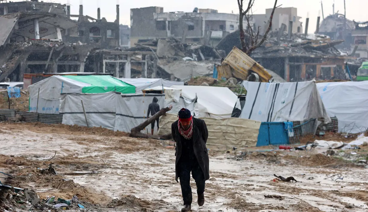 Seorang pria Palestina berjalan di depan tenda-tenda yang didirikan di tengah kehancuran di Beit Hanoun, Jalur Gaza utara pada 12 Februari 2025. (Omar AL-QATTAA/AFP)