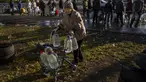 Perempuan lansia mendorong alat bantu jalan yang penuh dengan botol plastik setelah diisi ulang ke dalam tangki, di pusat kota Mykolaiv, Ukraina, Senin (24/10/2022). Sejak pertengahan April warga Mykolaiv telah hidup tanpa pasokan air minum. (AP Photo/Emilio Morenatti)