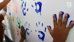 Siswa menempel tangan berlumuran cat air ke dinding di SD Negeri 15 Karet Tengsin, Jakarta, Rabu (18/10). Kegiatan ini digelar dalam rangka Hari Cuci Tangan Pakai Sabun Sedunia yang jatuh setiap tanggal 15 Oktober. (Liputan6.com/Fery Pradolo)