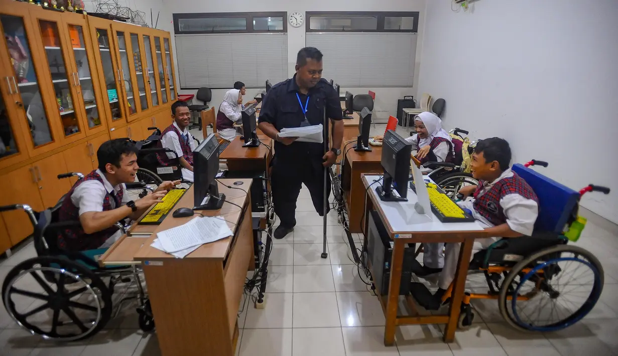 Pagi menjelang siang, suasana senyap menyelimuti ruangan kelas komputer. Pak Agung (39 tahun) berjalan hilir mudik mengawasi murid-murid penyandang disabilitas yang sedang mengerjakan tugas desain visual dengan menggunakan aplikasi canva. (merdeka.com/Arie Basuki)