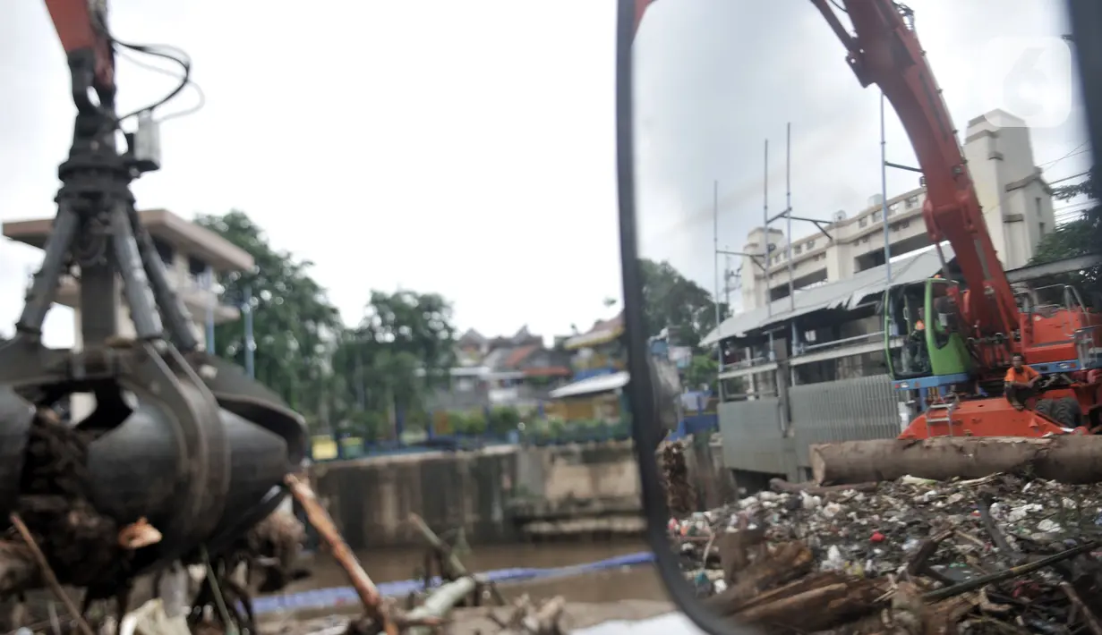 Petugas menggunakan alat berat saat mengangkut tumpukan sampah kiriman di Pintu Air Manggarai, Jakarta, Minggu (29/12/2019). Jenis sampah yang memenuhi Pintu Air Manggarai seperti batang pohon, balok kayu, plastik, hingga limbah rumah tangga. (merdeka.com/Iqbal Nugroho)