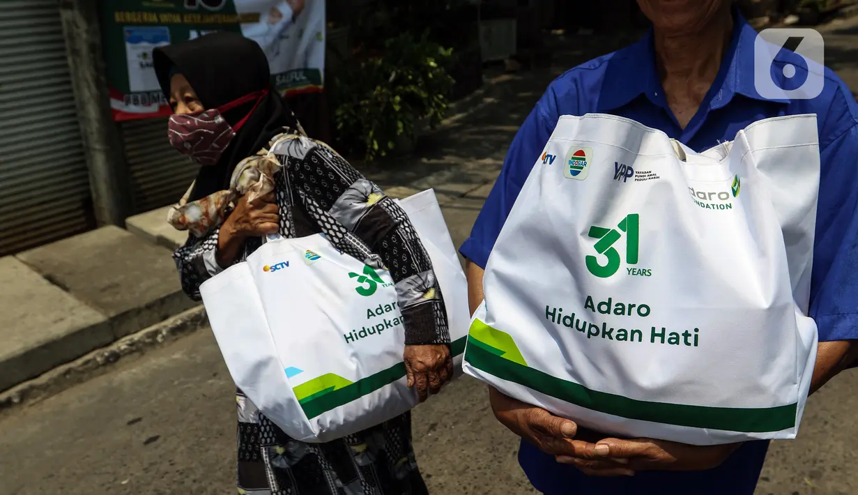 Warga membawa sembako yang di bagikan oleh PT Adaro Energi Tbk bersama Yayasan Pundi Amal Peduli Kasih (YPP) SCTV dan Indosiar di Jakarta, Rabu (4/10/2023). Dalam rangka Hari Ulang Tahun (HUT) Adaro ke-31 dengan tema “Adaro Hidupkan Hati” membagikan sembako sebanyak 2.000 paket  kepada masyarakat yang betul-betul memerlukan yang saat ini kurang beruntung di tengah beberapa harga sembako yang alami kenaikan. (Liputan6.com/Angga Yuniar)