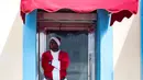 Seorang pria mengenakan pakaian Santa Claus menunggu pelanggan di pintu masuk sebuah kafe di Havana, Kuba (28/12). Havana merupakan kota terbesar dan pelabuhan utama di Kepulauan Hindia Barat. (AP Photo / Desmond Boylan)