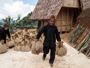 Warga bersiap meletakkan tumpukan padi di lumbung kayu tradisional di atas panggung, yang dikenal masyarakat setempat sebagai leuit, dalam perayaan panen Seren Taun di Sukabumi, Jawa Barat, pada Minggu 5 Oktober 2025. (Aditya AJI/AFP)