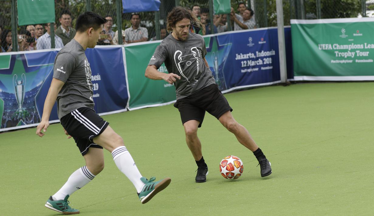 Legenda Barcelona, Carles Puyol, berusaha melewati pemain saat bermain futsal di Lapangan Menara Imperium, Jakarta, Selasa (12/3). Pertandingan tersebut merupakan bagian dari kegiatan UEFA Champions League Trophy Tour di Jakarta. (Bola.com/M Iqbal Ichsan)