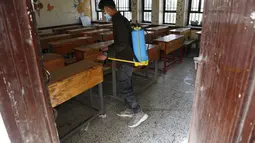 Seorang petugas kesehatan mendisinfeksi sebuah ruang kelas sebelum para siswa datang untuk mengikuti ujian di sebuah sekolah di Sanaa, Yaman (30/8/2020). (Xinhua/Mohammed Mohammed)