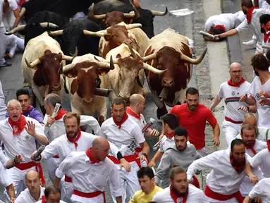 Peserta bersuka ria berlari di samping banteng selama Festival San Fermin di Pamplona, Spanyol, Senin (9/7). Festival berbahaya ini diikuti oleh peserta dari seluruh penjuru dunia. (AP Photo/Alvaro Barrientos)