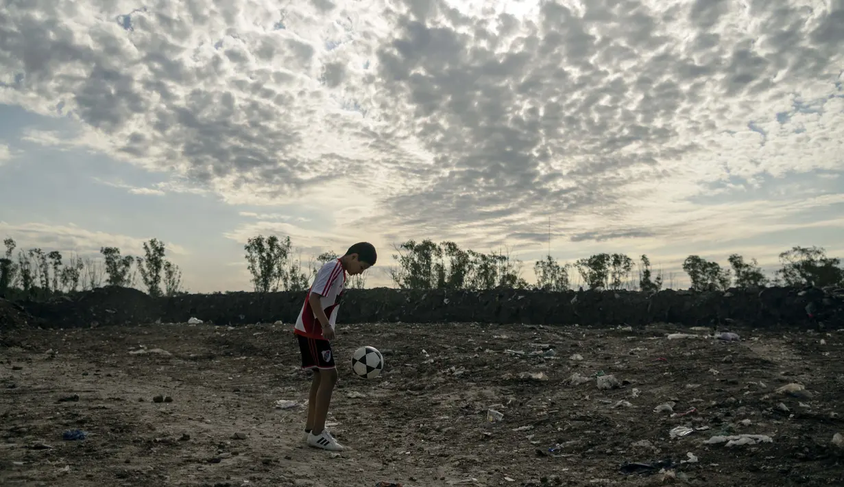 Daniel Dorado berlatih di tempat pembuangan sampah dekat rumahnya di daerah kumuh Costa Eperanza, Buenos Aires, 12 September 2020. Karena pandemi, Daniel yang bercita-cita menjadi pesepak bola di klub River Plate kini berlatih di rumah dengan instruksi dari pelatihnya. (ARIEL TIMY TORRES/AFP)