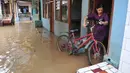 Warga memindahkan sepedanya menyusul surutnya air yang sempat merendam pemukiman mereka di kawasan Kampung Pulo, Kelurahan Kampung Melayu, Jatinegara, Jakarta, Selasa, (17/11). (Liputan6.com/Gempur M Surya)