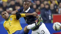 Penyerang Brasil, Douglas Costa (kiri) berebut bola dengan bek Prancis Patrice Evra saat laga persahabatan di Stade de France, Prancis, Jumat (27/3/2015 ). Brasil menang 3-1 atas Prancis. (REUTERS/Charles Platiau)