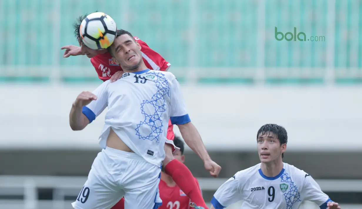 Duel pemain  Uzbekistan, Gofurov Husniddin (tengah) dengan pemain Korea Utara pada PSSI Anniversary Cu 2018 di Stadion Pakansari, Bogor, (26/4/2018). Uzbekistan bermain imbang  2-2. (Bola.com/Nick Hanoatubun)