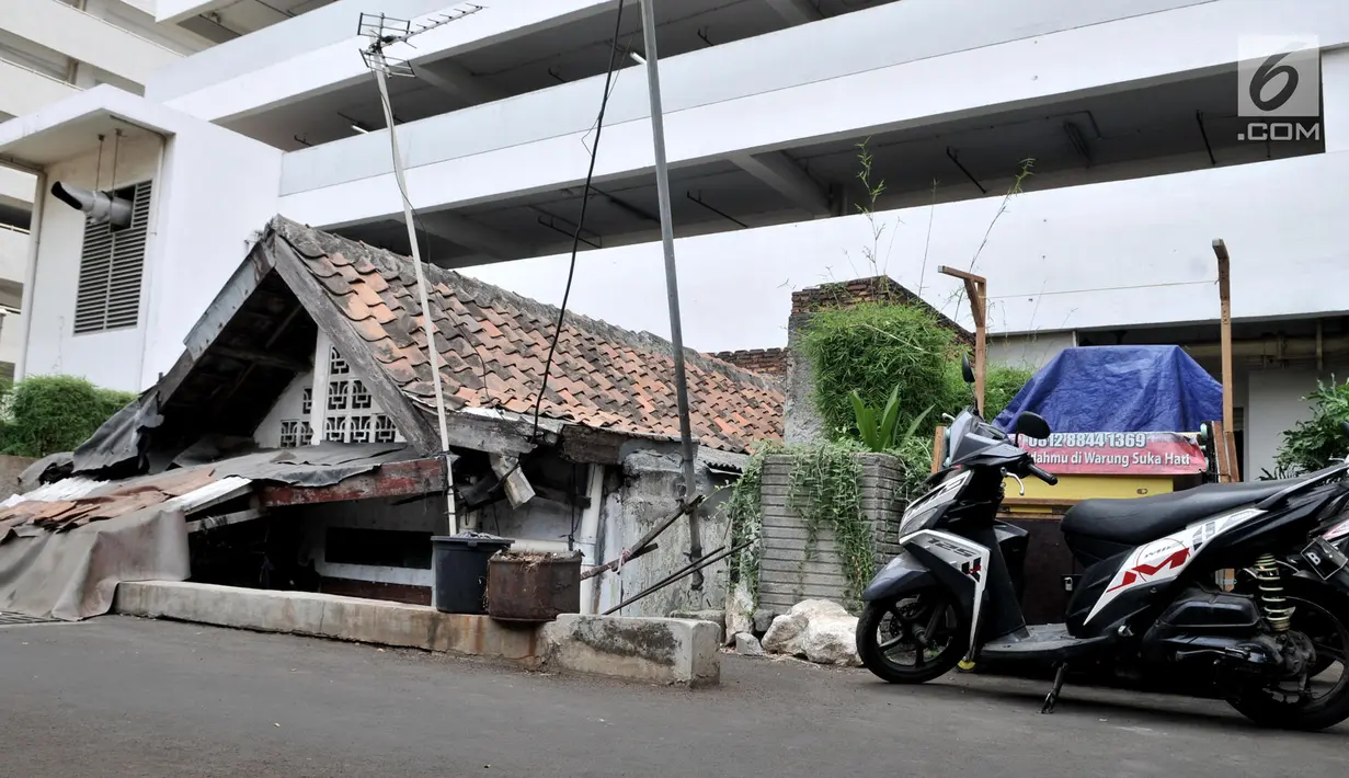 Sebuah motor terparkir di dekat sebuah rumah usang di halaman belakang apartemen Thamrin Executive Residence, Kebon Melati, Jakarta, Minggu (22/9/2019). Bertahan di tengah gedung pencakar langit membuat pemilik rumah harus berebut air bersih dengan apartemen. (merdeka.com/Iqbal S Nugroho)