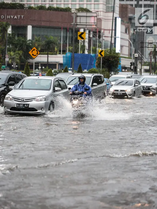 Sejumlah kendaraan melintas menerjang genangan air di kawasan Bunderan HI, Jakarta, Kamis (22/11). Genangan air hujan setinggi 40 cm tersebut disebabkan hujan deras yang melanda Jakarta pada siang hari. (Liputan6.com/Faizal Fanani)