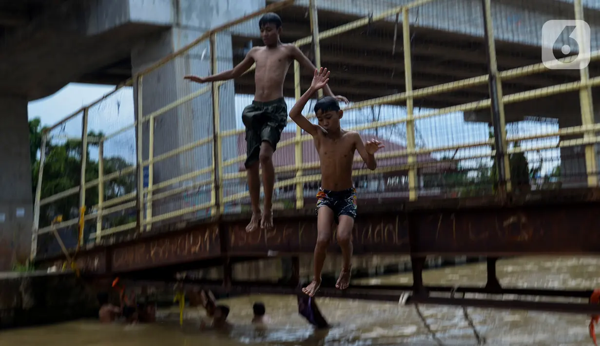 Anak-anak bermain dan berenang di aliran Kalimalang, Jakarta, Sabtu (15/2/2020). Cuaca yang tidak menentu membuat aliran air terkadang menjadi deras sehingga akan membahayakan keselamatan anak-anak saat bermain dan berenang. (merdeka.com/Imam Buhori)