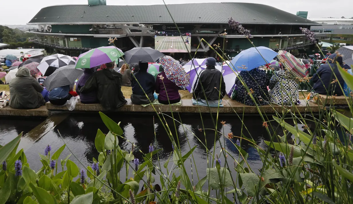 Antusias penonton  saat menyaksikan laga tenis Wimbledon dari layar tanpa mempedulikan hujan di The All England Lawn Tennis Club, London, (11/7/2017). (AP/Kirsty Wigglesworth)