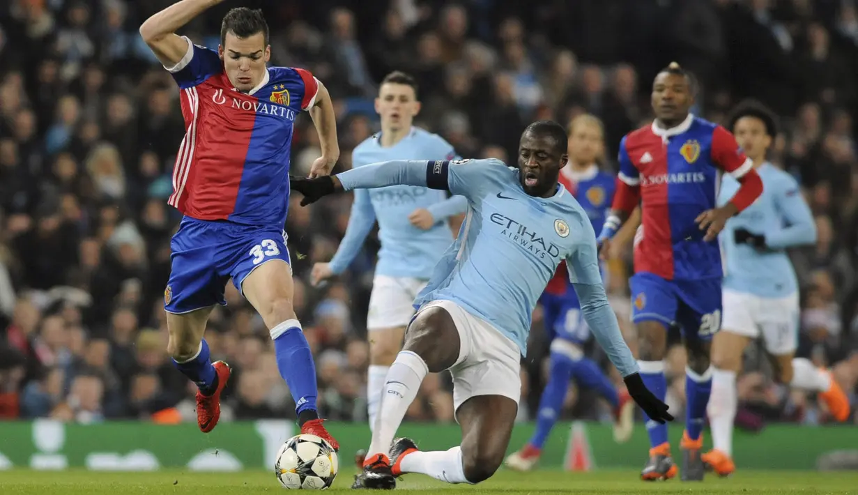 Gelandang Manchester City, Yaya Toure, berusaha menghadang pemain FC Basel, Kevin Bua, pada laga Liga Champions di Stadion Etihad, Rabu (7/3/2018). Manchester City takluk 1-2 dari FC Basel. (AP/Rui Vieira)