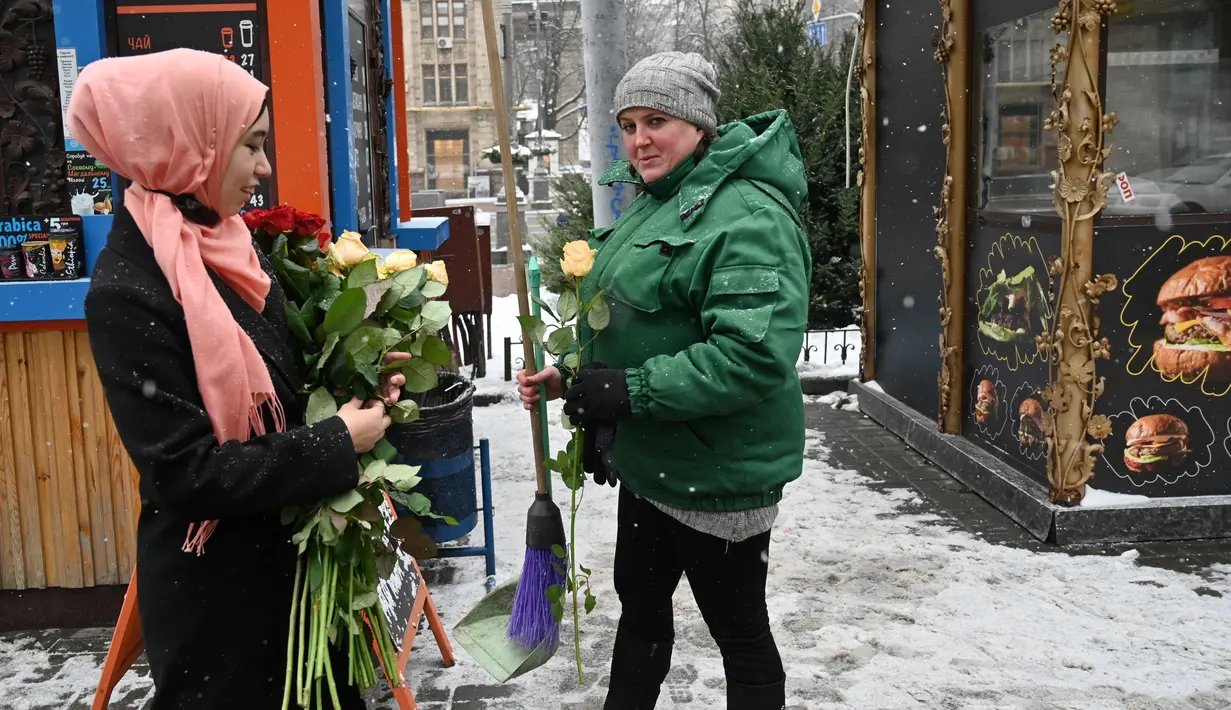 Seorang aktivis dari Asosiasi Perempuan Muslim Ukraina memberikan bunga kepada pejalan kaki selama perayaan World Hijab Day di pusat kota Kiev, Senin (1/2/2021). Hari Hijab Sedunia merupakan gagasan Nazma Khan di New York, Amerika Serikat pada tahun 2013. (Sergei SUPINSKY/AFP)