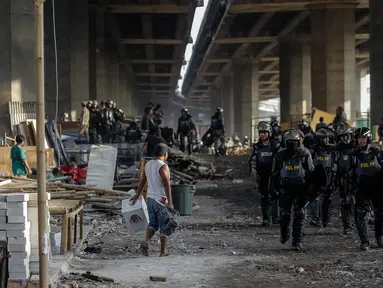 Petugas Satpol PP dengan pakaian anti huru hara lengkap mengamankan kegiatan penertiban bedeng liar di bawah kolong Tol Teluk Intan, Jakarta, Rabu (14/6). (Liputan6.com/Faizal Fanani)