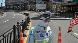 Seorang petugas transit mengenakan pakaian pelindung mengontrol akses ke jembatan ke arah distrik Pudong dalam penguncian sebagai tindakan pencegahan virus corona Covid-19  di Shanghai (29/3/2022). (AFP/Hector Retamal)