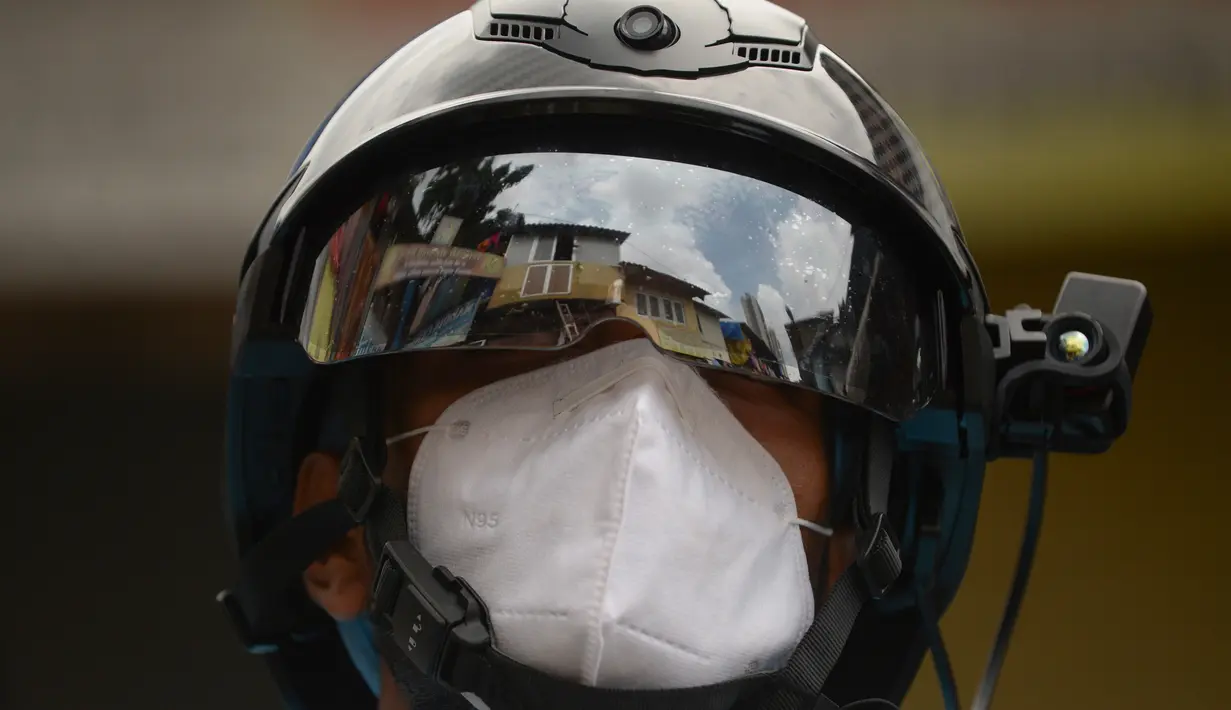 Sukarelawan petugas kesehatan dari LSM India Bharatiya Jain Sanghatana mengenakan helm pintar untuk melakukan screening kasus COVID-19 dari pintu ke pintu di Mumbai, 21 Juli 2020. Alat tersebut memungkinkan petugas Kesehatan mencatat suhu puluhan penduduk per menit. (INDRANIL MUKHERJEE/AFP)
