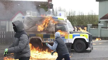 Pemuda bertopeng melemparkan bom molotov ke mobil polisi saat pengunjuk rasa Republikan yang menentang Perjanjian Jumat Agung mengadakan pawai di Londonderry, Irlandia Utara, Senin (10/4/2023). (AP Photo/Peter Morrison)