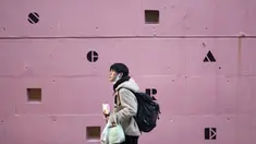 Seorang pria yang meletakkan masker wajah di bawah dagunya sambil makan makanan ringan berjalan melewati sekolah bahasa asing di Tokyo, Jepang,  Kamis (4 /2/2021). Tokyo mengonfirmasi lebih dari 730 kasus baru COVID-19 pada 4 Februari 2021. (AP Photo/Hiro Komae)