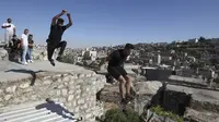 Pemuda Palestina Hammam Abu Sneineh (kiri) dan Abdallah al-Natsheh berlatih parkour di atas atap dan tangga rumah batu tradisional di Kota Hebron, Tepi Barat, Sabtu (5/6/2021). (HAZEM BADER/AFP)