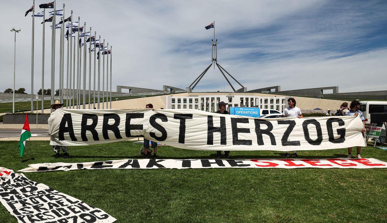 Selama di Australia, Presiden Israel, Isaac Herzog, dijadwalkan akan menghadiri upacara penghormatan bagi korban penembakan di Bondi Beach yang terjadi pada Desember 2025, yang menargetkan perayaan Hanukkah. Tampak dalam foto, para pengunjuk rasa berkumpul di depan gedung Parlemen menjelang pertemuan antara Perdana Menteri Australia Anthony Albanese dan Presiden Israel Isaac Herzog di Canberra pada Rabu 11 Februari 2026. (David GRAY/AFP)