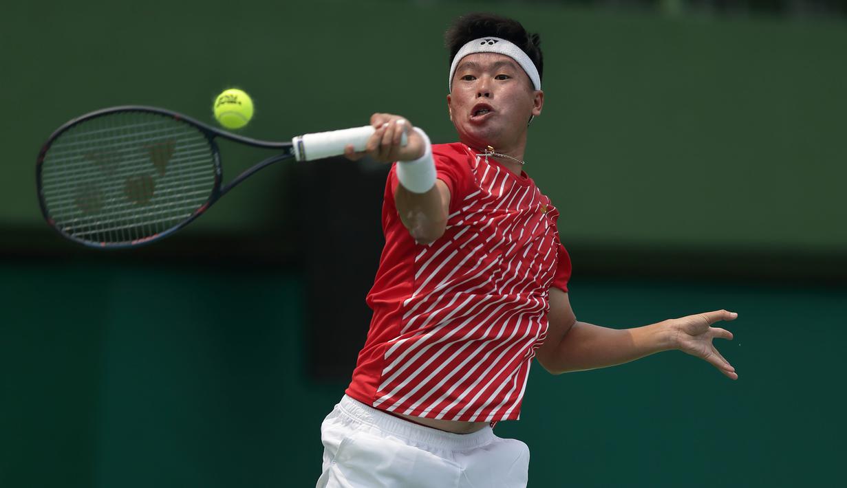 Petenis Indonesia, David A. Santoso, berusaha mengembalikan bola saat melawan petenis Selandia Baru, Rhett Purcell, pada laga Piala Davis 2019 Grup II Zona Asia/Oceania di Stadion Tenis GBK, Jakarta, Sabtu (14/9). David kalah  6-3, 4-6, 0-6 dari Rhett. (Bola.com/Peksi Cahyo)