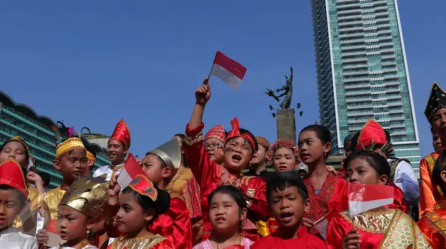 Seorang murid sekolah minggu Gereja Eban Haezer mengenakan baju adat sambil melambaikan bendera nasional di Bundaran HI Jakarta, Minggu (21/8). Menyanyikan lagu Indonesia Raya dan lagu daerah, mereka memperingati HUT RI ke 71. (Liputan6.com/Angga Yuniar)