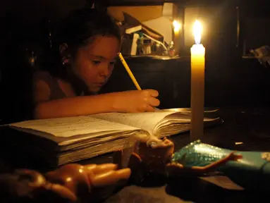 Seorang anak belajar dengan menggunakan lilin akibat pemadaman listrik di San Cristobal, Venezuela, Senin (25/4). Venezuela menerapkan pemadaman listrik selama empat jam sehari untuk menghadapi krisis energi yang memburuk. (REUTERS/Carlos Eduardo Ramirez)