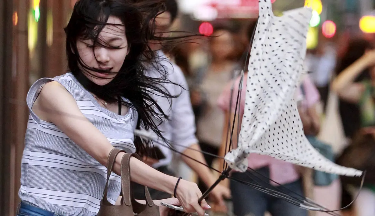 Seorang wanita memegang payung yang rusak akibat tiupan angin Topan Soudelor mendekati wilayah Taipei, Taiwan, (7/8/2015). Kuatnya angin yang disebabkan oleh efek Topan Soudelor membuat payung yang digunakan para pejalan kaki rusak. (REUTERS/Pichi Chuang)
