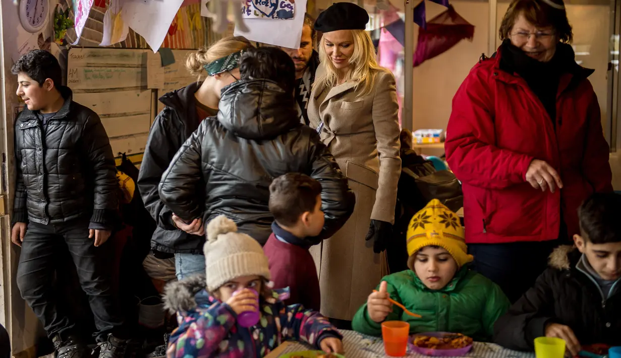 Aktris asal Kanada, Pamela Anderson mengunjungi kelas untuk anak-anak pengungsi di kamp Grande-Synthe, Prancis (25/1). Dalam kunjungannya, Pamela menyumbangkan buku anak-anak, makanan serta perlengkapan lainnya. (AFP/Philippe Huguen)