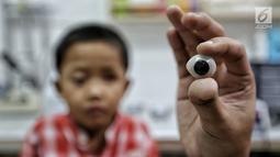 Sebuah bola mata palsu ditunjukkan sebelum dipasang di mata pasien anak di Klinik Ilyarsi Okularis, Villa Bintaro Indah, Tangsel, Selasa (15/5). Pembagian 23 mata palsu gratis merupakan donasi dari 8 anak perusahaan BUMN. (Liputan6.com/Fery Pradolo)