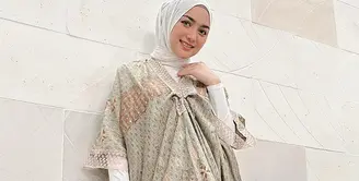 Di sini, Citra Kirana berpose mengenakan kaftan bermotif batik dengan nuansa warna hijau dan cokelat. Kaftan lengan pendek ini dipadukannya dengan manset dan jilbab putih polos. Foto: Instagram.