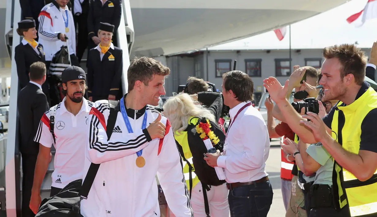 Pemain depan Timnas Jerman, Thomas Mueller, memberikan acungan jempol kepada para suporter sesaat setelah mendarat di Bandara Tegel, Berlin, (15/7/2014). (REUTERS/Karina Hessland/Pool)