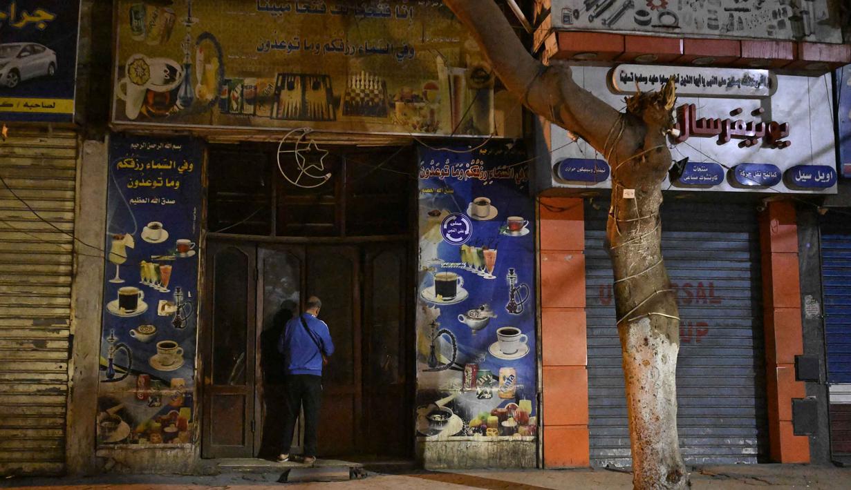 Kebijakan ini diambil oleh Perdana Menteri, Mostafa Madbouly, untuk menekan konsumsi listrik nasional setelah biaya impor energi melonjak tajam akibat konflik regional yang mengganggu pasokan minyak dan gas. Tampak dalam foto, seorang pemilik toko menutup tokonya di pusat kota Kairo, Mesir, pada Kamis 2 April 2026. (Khaled DESOUKI/AFP)