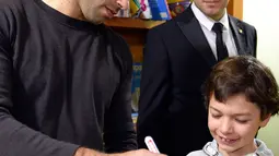 Pemain Barcelona, Javier Mascherano memberikan tanda tangannya kepada salah satu pasien anak saat melakukan kunjungan amal di Rumah Sakit Barcelona, Senin (4/1/2016). (AFP PHOTO / Lluis GENE)