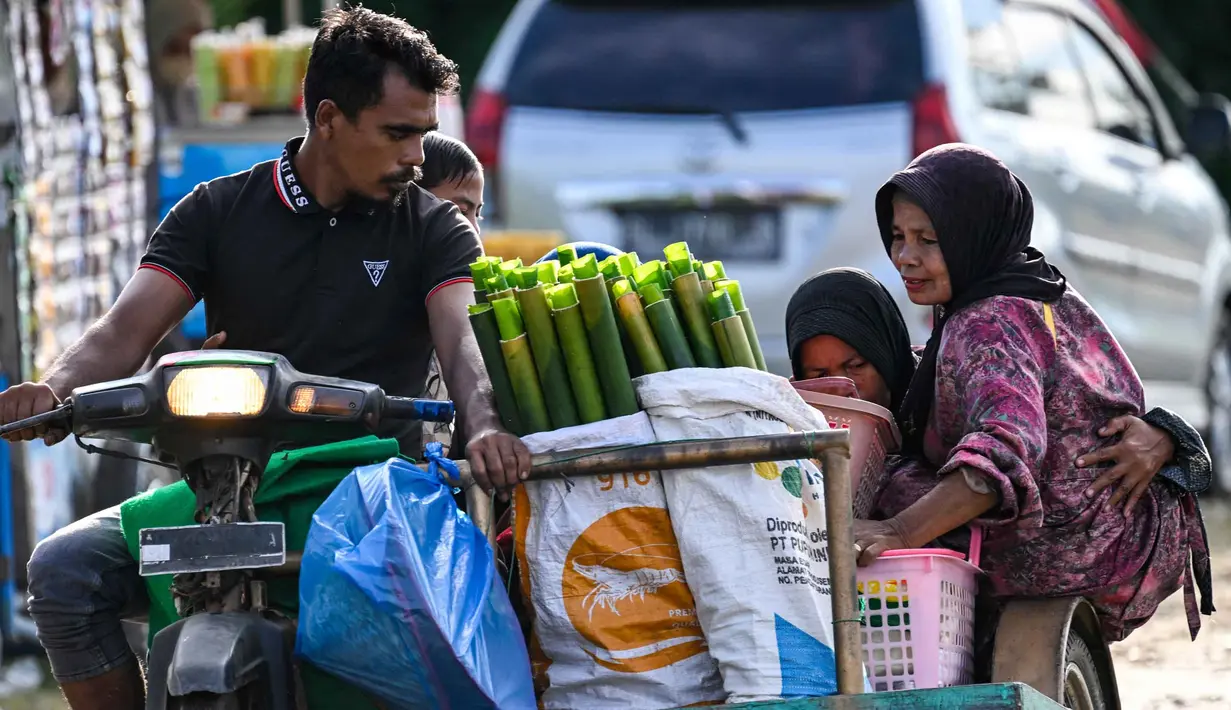 Para peserta mengangkut tabung bambu yang dilapisi daun pisang yang digunakan untuk memasak lemang, hidangan nasi ketan tradisional yang dimasukkan ke dalam tabung bambu dan diisi dengan santan yang kemudian diletakkan di atas api, selama acara memasak massal di Blang Pidie, Kabupaten Aceh Barat Daya, Aceh, pada Sabtu 25 April 2026. (CHAIDEER MAHYUDDIN/AFP)