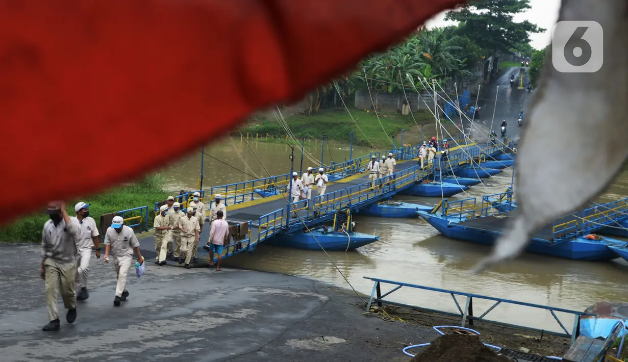 Pejalan kaki berjalan melintasi jembatan perahu di atas Sungai Citarum, Karawang, Jawa Barat, Sabtu (20/11/2021). Jembatan perahu ini menjadi jalan alternatif yang menghubungkan antara Desa Anggadita dengan Kawasan Pabrik Dusun Rumambe 1. (merdeka.com/Imam Buhori)