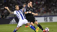 Pemain Real Madrid, Gareth Bale, berusaha melewati pemain Real Sociedad, Inigo Martinez. Bale berhasil mencetak dua gol kemenangan Los Blancos yang dibukukannya pada menit ke-2 dan 90+4. (AP/Alvaro Barrientos)