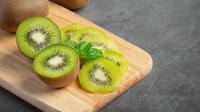 Buah kiwi utuh dan yang sudah dipotong di atas talenan (Foto Dok: Freepik/jcomp).