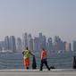 With the city skyline in the background, migrant workers rest at the Doha port, in Doha, Qatar, Sunday, Nov. 13, 2022. (AP Photo/Hassan Ammar)