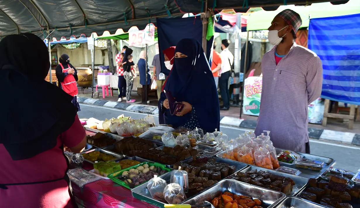 Orang-orang mengenakan masker saat membeli makanan di pasar menjelang berbuka puasa selama bulan suci Ramadan di Provinsi Narathiwat, Thailand, Selasa (5/5/2020). Ramadan kali ini berlangsung di tengah bayang-bayang virus corona COVID-19. (Madaree TOHLALA/AFP)