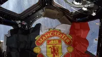 Bendera berlogo Manchester United berkibar di luar angkasa.