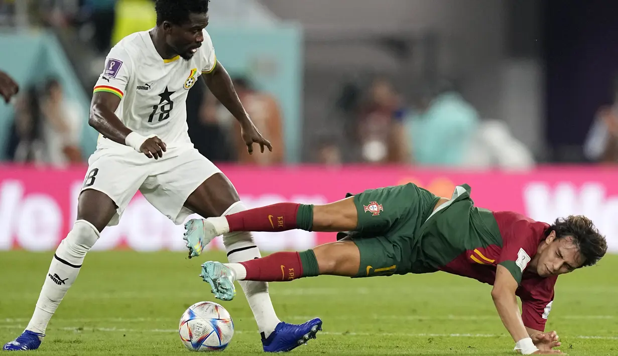 Bek Ghana Daniel Amartey berebut bola dengan penyerang Portugal Joao Felix pada duel grup H Piala Dunia 2022 di stadion 974, Kamis (24/11/2022).  Portugal berhasil memimpin klasemen grup H usai kemenangan 3-2 atas Ghana (AP Photo/Ariel Schalit)