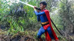 Pelajar bernama Rudiansyah dengan mengenakan kostum Superman membantu memadamkan kebakaran hutan dan lahan di Petuk Katimpun, Palangkaraya, Kalimantan Tengah, 17 Agustus 2026. (AFP/ Reina)