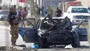 Seorang tentara berdiri di samping kendaraan yang rusak setelah serangan bom mobil di Kabul, Afghanistan (13/11/2019). Setidaknya tujuh orang tewas dan tujuh lainnya luka-luka ketika sebuah bom mobil meledak pada jam sibuk pagi hari Kabul pada 13 November. (AFP/STR)